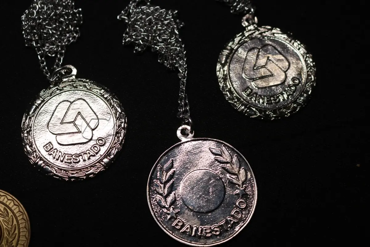 LOTE 045 - LOTE 45 – BANESTADO 	OBJETO	OBSERVAÇÕES 1.		Medalha Prateada Banestado – sem uso	3 unidades 2.		Medalha Associação Banestado – Inauguração Ginásio de Esportes-  30 de outubro de 1982	5 unidades 3.		Pin Banestado Feira do Paraná Super Plus Titulo de Capitalização.	3 unidades 4.		Pin CIN Centro Internacional de Negócios -  Banestado	1 unidade 5.		Pin 8ª Assembleia Geral da Federação Luterana Mundial – 1998 - Banestado	1 unidade 6.		Crachá de funcionário Banestado em metal	1 unidade 7.		Medalha Campeonato Paranaense de Natação – Associação Masters do Paraná. 2000. Banestado	1 unidade 8.		Medalha Honra ao Mérito - Banestado	1 unidade 9.		Alfinete de Lapela Banestado – Foz do Iguacu	1 unidade 10.		Alfinete de Lapela Banestado – Pato Branco	2 unidade