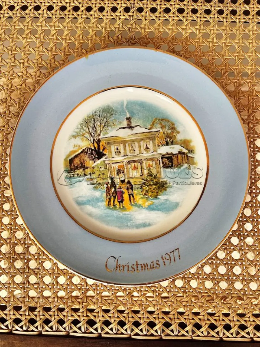 LOTE 030 - 01 LINDO PRATO DE NATAL DA SÉRIE AVON CHRISTMAS PLATE DE 1977, "CAROLLERS IN THE SNOW" - QUINTA EDIÇÃO DA SÉRIE. COM 22 CM DE DIÂMETRO E RETRATA UM GRUPO DE CANTORES DE NATAL EM FRENTE A UMA CASA DE DOIS ANDARES NO CENTRO. O VERSO MARCADO: SÉRIE DE PRATOS DE NATAL QUINTA EDIÇÃO "CANTORES DE NATAL NA NEVE" COM DOIS ANÉIS DE OURO 22K E O NATAL DE 1979 TAMBÉM EM OURO 22K.  FEITO EXCLUSIVAMENTE PARA A AVON CTS INC., 1977 POR ENOCH WEDGWOOD (TUNSTALL) LTD., INGLATERRA PEÇA COMPRADA EM GARAGEM DE ANTIGUIDADES NOS EUA. SUPORTE PARA PRATO NÃO INCLUÍDO NESTA VENDA. (NO ESTADO) ATENÇÃO! FAZER A VISITAÇÃO ANTES DE ARREMATAR, NÃO SABEMOS SE FUNCIONA, LEILÃO NÃO TEM GARANTIA E NEM DEVOLUÇÃO, SUJEITO A POSSÍVEIS AVARIAS VISÍVEIS/OCULTAS E/OU AUSÊNCIA DE COMPONENTES.