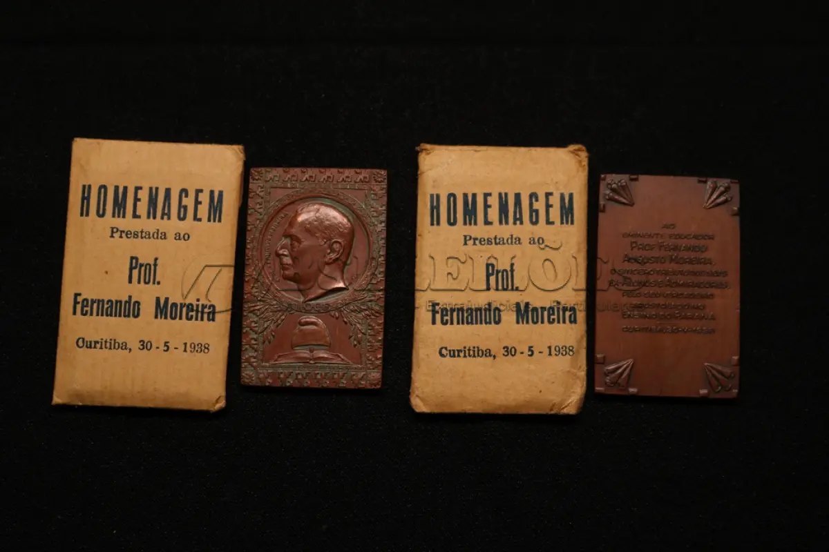 LOTE 020 - LOTE 20 – MEDALHAS FERNANDO MOREIRA 	MEDALHA	OBSERVAÇÕES 1.		Homenagem ao Professor Fernando Augusto Moreira. 1938. Gravador: José Peón	Acobreada - envelope original da medalha. 2.		Homenagem ao Professor Fernando Augusto Moreira. 1938. Gravador: José Peón	Acobreada - envelope original da medalha.