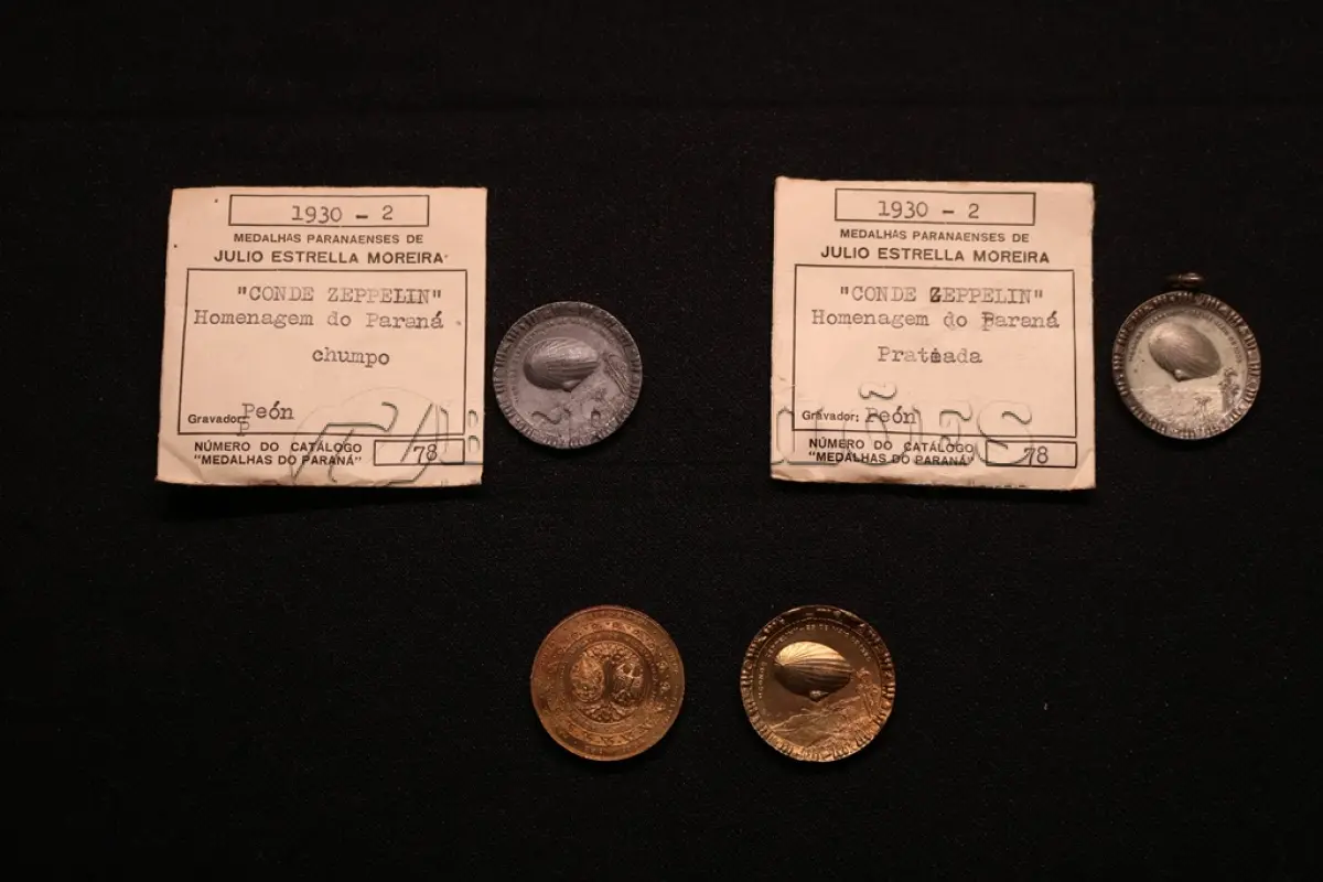 LOTE 031 - LOTE 31 – MEDALHAS CONDE ZEPPELIN 	MEDALHA	OBSERVAÇÕES 1.		Medalha Conde Zeppelin. Curitiba. 1930  Gravador: José Peón	Prateada – envelope da Coleção Júlio Estrella Moreira 2.		Medalha Conde Zeppelin. Curitiba. 1930  Gravador: José Peón	Chumbo – envelope da Coleção Júlio Estrella Moreira 3.		Medalha Conde Zeppelin. Curitiba. 1930  Gravador: José Peón	Dourada 4.		Medalha Conde Zeppelin. Curitiba. 1930  Gravador: José Peón	Dourada