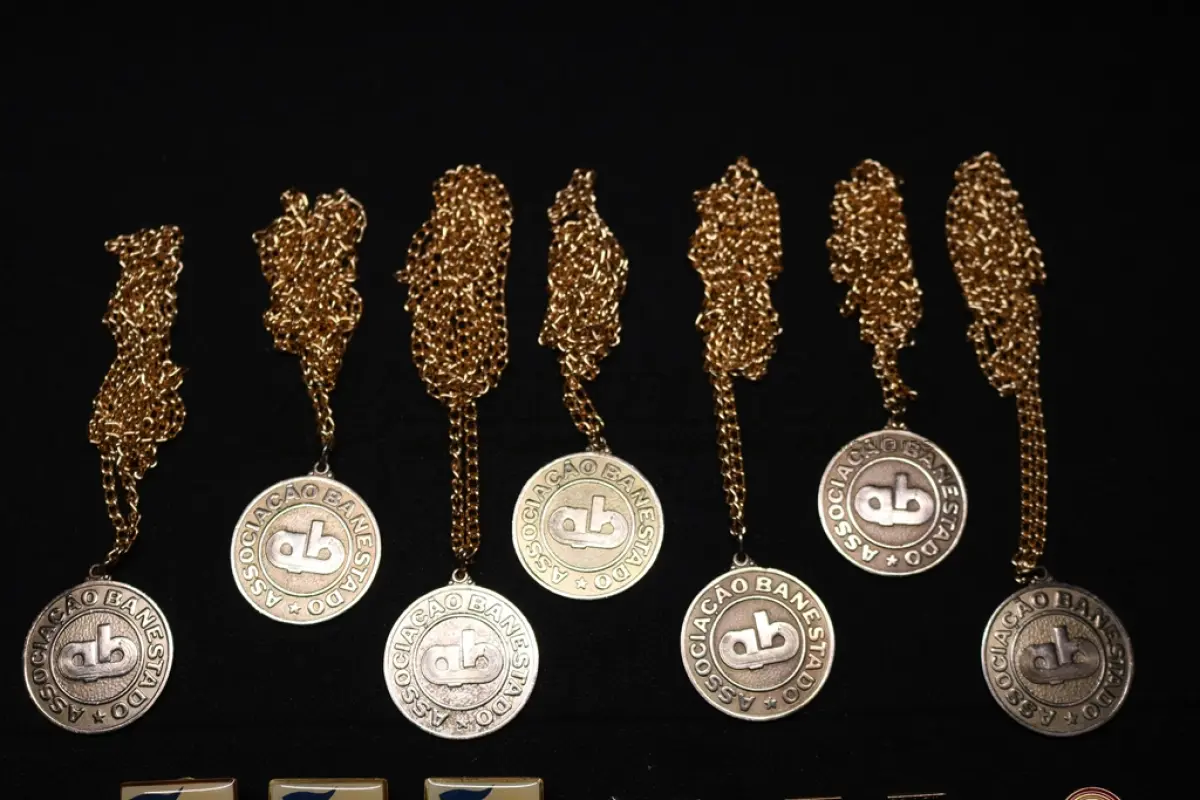 LOTE 046 - LOTE 46 – BANESTADO 	OBJETO	OBSERVAÇÕES 1.		Medalha Prateada Banestado – sem uso	3 unidades 2.		Medalha Associação Banestado – Inauguração Ginásio de Esportes-  30 de outubro de 1982	7 unidades 3.		Pin Banestado Feira do Paraná Super Plus Titulo de Capitalização.	3 unidades 4.		Pin CIN Centro Internacional de Negócios - Banestado	1 unidade 5.		Pin 8ª Assembleia Geral da Federação Luterana Mundial – 1998 - Banestado	2 unidades 6.		Crachá de funcionário Banestado em metal	1 unidade 7.		Chaveiro Banestado de metal e couro	1 unidade 8.		Alfinete de Lapela Banestado – Foz do Iguacu	1 unidade 9.		Alfinete de Lapela Banestado – Pato Branco	1 unidade