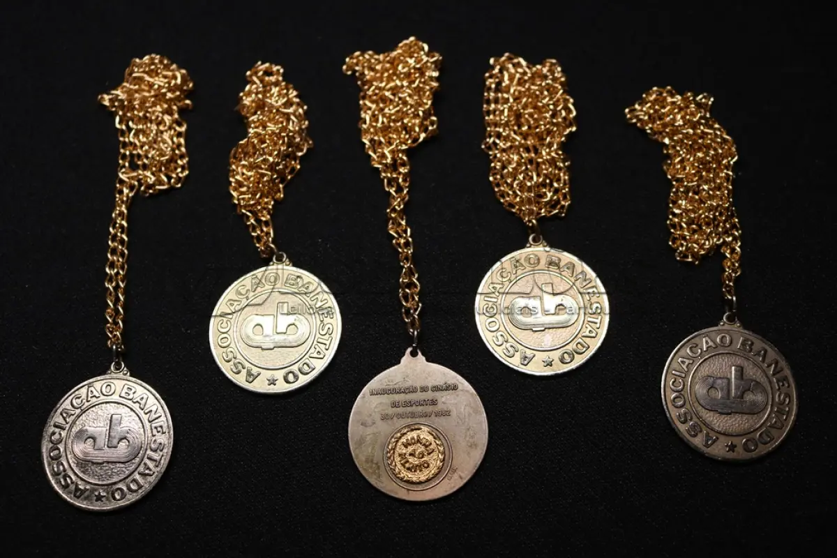 LOTE 045 - LOTE 45 – BANESTADO 	OBJETO	OBSERVAÇÕES 1.		Medalha Prateada Banestado – sem uso	3 unidades 2.		Medalha Associação Banestado – Inauguração Ginásio de Esportes-  30 de outubro de 1982	5 unidades 3.		Pin Banestado Feira do Paraná Super Plus Titulo de Capitalização.	3 unidades 4.		Pin CIN Centro Internacional de Negócios -  Banestado	1 unidade 5.		Pin 8ª Assembleia Geral da Federação Luterana Mundial – 1998 - Banestado	1 unidade 6.		Crachá de funcionário Banestado em metal	1 unidade 7.		Medalha Campeonato Paranaense de Natação – Associação Masters do Paraná. 2000. Banestado	1 unidade 8.		Medalha Honra ao Mérito - Banestado	1 unidade 9.		Alfinete de Lapela Banestado – Foz do Iguacu	1 unidade 10.		Alfinete de Lapela Banestado – Pato Branco	2 unidade