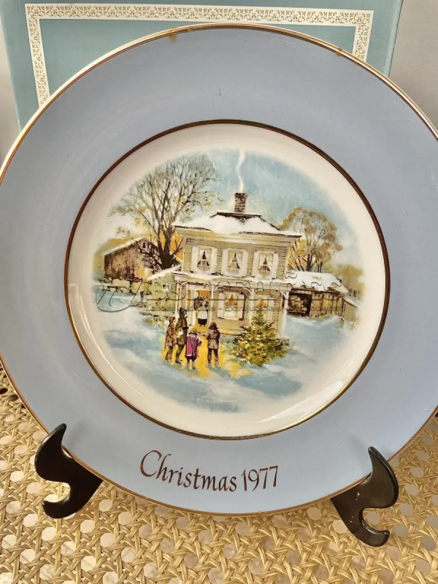 LOTE 030 - 01 LINDO PRATO DE NATAL DA SÉRIE AVON CHRISTMAS PLATE DE 1977, "CAROLLERS IN THE SNOW" - QUINTA EDIÇÃO DA SÉRIE. COM 22 CM DE DIÂMETRO E RETRATA UM GRUPO DE CANTORES DE NATAL EM FRENTE A UMA CASA DE DOIS ANDARES NO CENTRO. O VERSO MARCADO: SÉRIE DE PRATOS DE NATAL QUINTA EDIÇÃO "CANTORES DE NATAL NA NEVE" COM DOIS ANÉIS DE OURO 22K E O NATAL DE 1979 TAMBÉM EM OURO 22K.  FEITO EXCLUSIVAMENTE PARA A AVON CTS INC., 1977 POR ENOCH WEDGWOOD (TUNSTALL) LTD., INGLATERRA PEÇA COMPRADA EM GARAGEM DE ANTIGUIDADES NOS EUA. SUPORTE PARA PRATO NÃO INCLUÍDO NESTA VENDA. (NO ESTADO) ATENÇÃO! FAZER A VISITAÇÃO ANTES DE ARREMATAR, NÃO SABEMOS SE FUNCIONA, LEILÃO NÃO TEM GARANTIA E NEM DEVOLUÇÃO, SUJEITO A POSSÍVEIS AVARIAS VISÍVEIS/OCULTAS E/OU AUSÊNCIA DE COMPONENTES.