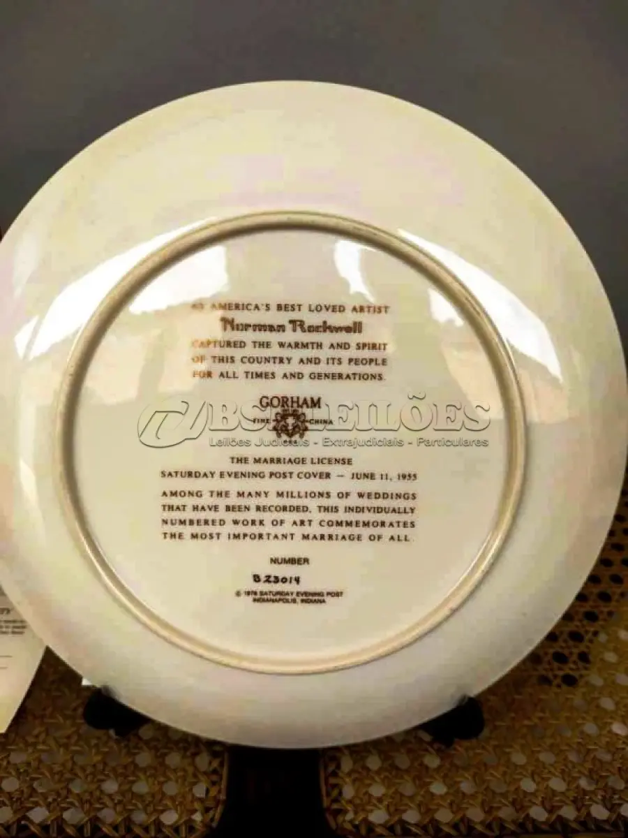 LOTE 068 - 01 RARO E GRANDE PRATO ASSINADO POR NORMAN ROCKWELL, COM 26,50 CM DE DIÂMETRO EDIÇÃO LIMITADA, COM CERTIFICADO DE AUTENTICIDADE EM TONS QUENTES DE MARROM E AMARELO SUAVE, CAPTURA UM MOMENTO ATEMPORAL DE AMOR E COMPROMISSO. A CENA MOSTRA UM CASAL ELEGANTEMENTE VESTIDO ASSINANDO SUA CERTIDÃO DE CASAMENTO. UM CELEBRANTE, SENTADO PRÓXIMO, OBSERVA O MOMENTO COM UMA EXPRESSÃO GENTIL, ADICIONANDO UM TOQUE DE SERIEDADE E TRADIÇÃO À COMPOSIÇÃO. O PRATO  COM ELEGANTES DETALHES DOURADOS NAS BORDAS, REALÇANDO SEU TOQUE CLÁSSICO E SOFISTICADO.UMA BELA REPRESENTAÇÃO DA CAPACIDADE DE ROCKWELL DE CAPTURAR MOMENTOS ÍNTIMOS DA VIDA COM CHARME E DETALHES. ITEM COMPRADO EM GARAGEM DE ANTIGUIDADES NOS EUA.SUPORTE PARA PRATO NÃO INCLUÍDO NESTA VENDA.SUPORTE PARA PRATO NÃO INCLUÍDO NESTA VENDA. (NO ESTADO) ATENÇÃO! FAZER A VISITAÇÃO ANTES DE ARREMATAR, NÃO SABEMOS SE FUNCIONA, LEILÃO NÃO TEM GARANTIA E NEM DEVOLUÇÃO, SUJEITO A POSSÍVEIS AVARIAS VISÍVEIS/OCULTAS E/OU AUSÊNCIA DE COMPONENTES.