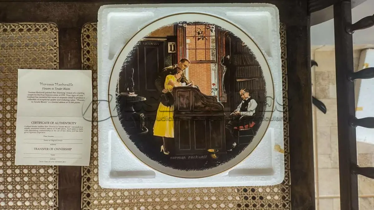 LOTE 068 - 01 RARO E GRANDE PRATO ASSINADO POR NORMAN ROCKWELL, COM 26,50 CM DE DIÂMETRO EDIÇÃO LIMITADA, COM CERTIFICADO DE AUTENTICIDADE EM TONS QUENTES DE MARROM E AMARELO SUAVE, CAPTURA UM MOMENTO ATEMPORAL DE AMOR E COMPROMISSO. A CENA MOSTRA UM CASAL ELEGANTEMENTE VESTIDO ASSINANDO SUA CERTIDÃO DE CASAMENTO. UM CELEBRANTE, SENTADO PRÓXIMO, OBSERVA O MOMENTO COM UMA EXPRESSÃO GENTIL, ADICIONANDO UM TOQUE DE SERIEDADE E TRADIÇÃO À COMPOSIÇÃO. O PRATO  COM ELEGANTES DETALHES DOURADOS NAS BORDAS, REALÇANDO SEU TOQUE CLÁSSICO E SOFISTICADO.UMA BELA REPRESENTAÇÃO DA CAPACIDADE DE ROCKWELL DE CAPTURAR MOMENTOS ÍNTIMOS DA VIDA COM CHARME E DETALHES. ITEM COMPRADO EM GARAGEM DE ANTIGUIDADES NOS EUA.SUPORTE PARA PRATO NÃO INCLUÍDO NESTA VENDA.SUPORTE PARA PRATO NÃO INCLUÍDO NESTA VENDA. (NO ESTADO) ATENÇÃO! FAZER A VISITAÇÃO ANTES DE ARREMATAR, NÃO SABEMOS SE FUNCIONA, LEILÃO NÃO TEM GARANTIA E NEM DEVOLUÇÃO, SUJEITO A POSSÍVEIS AVARIAS VISÍVEIS/OCULTAS E/OU AUSÊNCIA DE COMPONENTES.