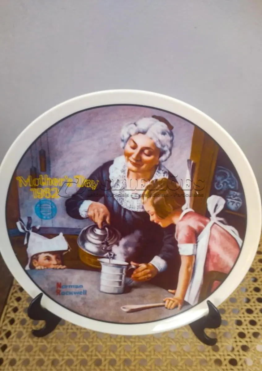 LOTE 179 - 01 PRATO DE NORMAN ROCKWELL PARA O DIA DAS MÃES DE 1982, "THE COOKING LESSON", DA PORCELANA FINA KNOWLES. O NÚMERO DO PRATO É 13025N , DA PRIMEIRA EDIÇÃO LIMITADA. O SÉTIMO DE UMA SÉRIE ANUAL PARA O DIA DAS MÃES. CERTIFICADO PELA ROCKWELL SOCIETY OF AMERICA. ESTE PRATO É UMA EDIÇÃO LIMITADA, PERMANENTEMENTE FECHADA, FEITA EM 7 DE MAIO DE 1982 PELA KNOWLES, A MARCA MAIS ANTIGA DA AMÉRICA EM PORCELANA FINA. O PRATO MEDE 21,8 CM DE DIÂMETRO E ESTÁ EM ÓTIMO ESTADO ITEM COMPRADO EM 2/10/1982 COM CERTIFICADO DE AUTENTICIDADE NOTAS E DOCUMENTOS DE COMPRA.  ITEM COMPRADO EM GARAGENS DE ANTIGUIDADES NOS EUA.SUPORTE PARA PRATO NÃO INCLUÍDO NESTA VENDA. (NO ESTADO) ATENÇÃO! FAZER A VISITAÇÃO ANTES DE ARREMATAR, NÃO SABEMOS SE FUNCIONA, LEILÃO NÃO TEM GARANTIA E NEM DEVOLUÇÃO, SUJEITO A POSSÍVEIS AVARIAS VISÍVEIS/OCULTAS E/OU AUSÊNCIA DE COMPONENTES.