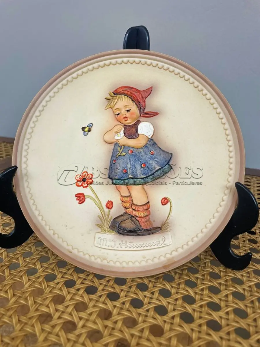 LOTE 313 - 01 RARO PRATO DE PORCELANA LINDAMENTE TRABALHADO DA FAMOSA M.J. HUMMEL GOEBEL APRESENTA UM FORMATO REDONDO E DESIGN MULTICOLORIDO, PERFEITO PARA TODAS AS OCASIÕES E ESTILOS DE DECORAÇÃO. É UM ITEM DE COLECIONADOR DA SEGUNDA EDIÇÃO DO PRATO VALENTINE JOY, GRAVADO COM DETALHES INTRINCADOS E FABRICADO NA ALEMANHA NA DÉCADA DE 1980.TERCEIRA EDIÇÃO DE UMA SÉRIE DE QUATRO PRATOS LANÇADOS PEÇA ÚNICA DA CULTURA ALEMÃ E VEM DA FRANQUIA GOEBEL, COM 16 CM DE DIÂMETROUMA MARCA RENOMADA NO SETOR DE COLECIONÁVEIS ​​DECORATIVOS. LANÇADA SOMENTE PARA MEMBROS DO CLUBE DE COLECIONADORES GOEBEL. ITEM COMPRADO EM GARAGENS DE ANTIGUIDADES NOS EUA.SUPORTE PARA PRATO NÃO INCLUÍDO NESTA VENDA. (NO ESTADO) ATENÇÃO! FAZER A VISITAÇÃO ANTES DE ARREMATAR, NÃO SABEMOS SE FUNCIONA, LEILÃO NÃO TEM GARANTIA E NEM DEVOLUÇÃO, SUJEITO A POSSÍVEIS AVARIAS VISÍVEIS/OCULTAS E/OU AUSÊNCIA DE COMPONENTES.