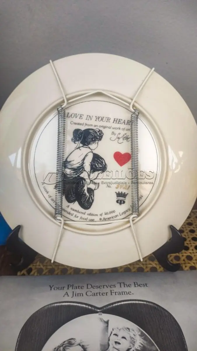 LOTE 139 - 01 LINDO PRATO DE COLECIONADOR DE SUE ETEM "LOVE IN YOUR HEART", ASSINADO À MÃO O PRATO TEM 21 CM É O Nº 5421 DE UMA EDIÇÃO LIMITADA DE 40.000 EXEMPLARES NO TOTAL DA AMERICAN LEGACY LTD. 1984 E RETRATA DUAS CRIANÇAS SE ABRAÇANDO. SUE ETEM É CONHECIDA POR SUAS BELAS REPRESENTAÇÕES DE CRIANÇAS EM CORES VIBRANTES E DIMENSÕES, E O PRATO É ASSINADO POR ELA NO VERSO, EM SUA CAIXA ORIGINAL. PEÇA COMPRADA EM GARAGEM DE ANTIGUIDADES NOS EUA. SUPORTE PARA PRATO NÃO INCLUÍDO NESTA VENDA. (NO ESTADO) ATENÇÃO! FAZER A VISITAÇÃO ANTES DE ARREMATAR, NÃO SABEMOS SE FUNCIONA, LEILÃO NÃO TEM GARANTIA E NEM DEVOLUÇÃO, SUJEITO A POSSÍVEIS AVARIAS VISÍVEIS/OCULTAS E/OU AUSÊNCIA DE COMPONENTES.