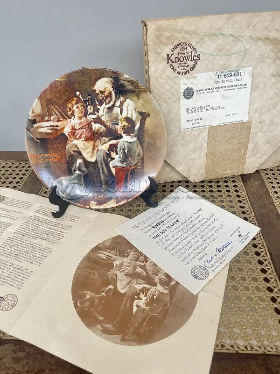 LOTE 271 - 01 PRATO THE TOY MAKER PRIMEIRO PARTO DE  ROCKWELL HERITAGE COLLECTION KNOWLES NORMAN ROCKWELL DATADO EM 1977 . ESTA É A PRIMEIRA PLACA DE COLECIONADOR DE EDIÇÃO LIMITADA Nº9857 D "THE TOY MAKER" DE NORMAN ROCKWELL NA HERITAGE COLLECTION. FOI FEITO À MÃO EM UMA EDIÇÃO LIMITADA PERMANENTEMENTE FECHADA EM 1977 POR KNOWLES E CERTIFICADA COMO "TRUE ROCKWELL CLASSIC" PELA ROCKWELL SOCIETY OF AMERICA.RETRATA UM VELHO FAZENDO UM BRINQUEDO COM UM MENINO E UMA MENINA OLHANDO ATENTAMENTE. HÁ UM CACHORRO ABAIXO DELES OLHANDO COM INTERESSE. COM TODA PAPELADA INCLUÍDA. CERTIFICADO DE AUTORIZAÇÃO DE USO (COA) E LIVRETO DE HISTÓRICO E CERTIFICADO DE AUTENTICIDADE. CAIXA ORIGINAL INCLUÍDA,. MEDE 21,5 CM DE DIÂMETRO. PROVÉM DE UMA COLEÇÃO PARTICULAR GUARDADA A ANOS NOS EUA.ITEM COMPRADO EM GARAGEM DE ANTIGUIDADES NOS EUA. SUPORTE PARA PRATO NÃO INCLUÍDO NESTA VENDA. (NO ESTADO) ATENÇÃO! FAZER A VISITAÇÃO ANTES DE ARREMATAR, NÃO SABEMOS SE FUNCIONA, LEILÃO NÃO TEM GARANTIA E NEM DEVOLUÇÃO, SUJEITO A POSSÍVEIS AVARIAS VISÍVEIS/OCULTAS E/OU AUSÊNCIA DE COMPONENTES.
