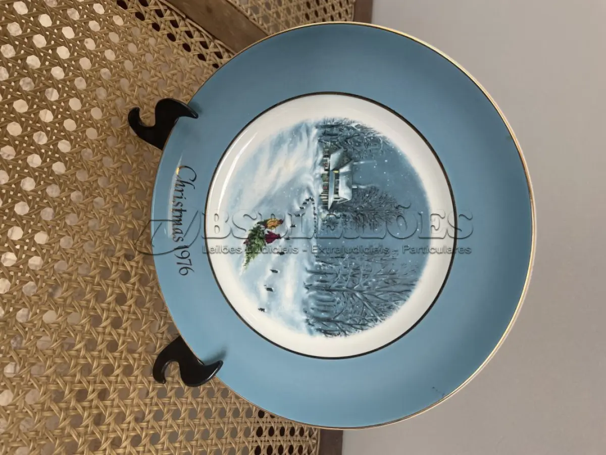 LOTE 299 - 01 LINDO PRATO DE NATAL DA SÉRIE AVON CHRISTMAS PLATE DE 1976, " BRINGING HOME THE TREE" - TERCEIRA  EDIÇÃO DA SÉRIE. COM 22 CM DE DIÂMETRO E RETRATA UM GRUPO DE PESSOAS PATINANDO NA NEVE . O VERSO MARCADO COM DOIS ANÉIS DE OURO 22K.FEITO EXCLUSIVAMENTE PARA A AVON CTS INC., 1976 POR ENOCH WEDGWOOD (TUNSTALL) LTD, INGLATERRA.PEÇA COMPRADA EM GARAGEM DE ANTIGUIDADES NOS EUA. SUPORTE PARA PRATO NÃO INCLUÍDO NESTA VENDA. (NO ESTADO) ATENÇÃO! FAZER A VISITAÇÃO ANTES DE ARREMATAR, NÃO SABEMOS SE FUNCIONA, LEILÃO NÃO TEM GARANTIA E NEM DEVOLUÇÃO, SUJEITO A POSSÍVEIS AVARIAS VISÍVEIS/OCULTAS E/OU AUSÊNCIA DE COMPONENTES.