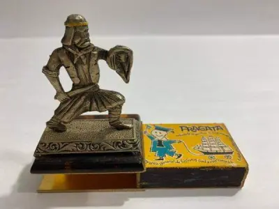 LOTE 035 - ANTIGO PORTA CAIXA FOSFORO SAMURAI DE METAL (NO ESTADO)