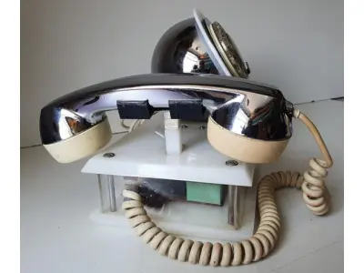 LOTE 084 - RARO TELEFONE ANOS 70. EM PLÁSTICO CROMADO E MECANISMO EM CAIXA DE ACRÍLICO MEDIDAS 24 CM COMP X 14,5 CM LARG X 19 CM ALT (NO ESTADO)