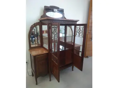 LOTE 040 - 01 CRISTALEIRA ANTIGA IMBUIA COM DETALHES ENTALHADOS NAS PORTAS, ESPELHOS LATERAIS, COM PORTA ENVIDRAÇADA EM CRISTAL BISOTADO. (NO ESTADO DE CONSERVAÇÃO QUE SE ENCONTRA) 