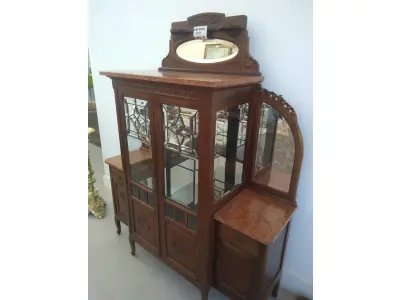 LOTE 040 - 01 CRISTALEIRA ANTIGA IMBUIA COM DETALHES ENTALHADOS NAS PORTAS, ESPELHOS LATERAIS, COM PORTA ENVIDRAÇADA EM CRISTAL BISOTADO. (NO ESTADO DE CONSERVAÇÃO QUE SE ENCONTRA) 