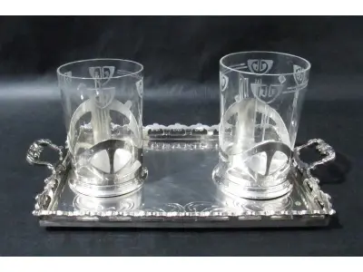 LOTE 290 - DOIS COPOS EM CRISTAL TRANSLÚCIDO COM SUPORTE DE METAL PRATEADO UMA (1) BANDEJA EM FORMATO RETANGULAR CONFECCIONADO EM METAL ESPESSURADO A PRATA 26,4 CM DE COMPRIMENTO (NO ESTADO)