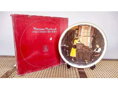 01 RARO E GRANDE PRATO ASSINADO POR NORMAN ROCKWELL, COM 26,50 CM DE DIÂMETRO EDIÇÃO LIMITADA, COM CERTIFICADO DE AUTENTICIDADE EM TONS QUENTES DE MARROM E AMARELO SUAVE, CAPTURA UM MOMENTO ATEMPORAL DE AMOR E COMPROMISSO. A CENA MOSTRA UM CASAL ELEGANTEMENTE VESTIDO ASSINANDO SUA CERTIDÃO DE CASAMENTO. UM CELEBRANTE, SENTADO PRÓXIMO, OBSERVA O MOMENTO COM UMA EXPRESSÃO GENTIL, ADICIONANDO UM TOQUE DE SERIEDADE E TRADIÇÃO À COMPOSIÇÃO. O PRATO  COM ELEGANTES DETALHES DOURADOS NAS BORDAS, REALÇANDO SEU TOQUE CLÁSSICO E SOFISTICADO.UMA BELA REPRESENTAÇÃO DA CAPACIDADE DE ROCKWELL DE CAPTURAR MOMENTOS ÍNTIMOS DA VIDA COM CHARME E DETALHES. ITEM COMPRADO EM GARAGEM DE ANTIGUIDADES NOS EUA.SUPORTE PARA PRATO NÃO INCLUÍDO NESTA VENDA.SUPORTE PARA PRATO NÃO INCLUÍDO NESTA VENDA. (NO ESTADO) ATENÇÃO! FAZER A VISITAÇÃO ANTES DE ARREMATAR, NÃO SABEMOS SE FUNCIONA, LEILÃO NÃO TEM GARANTIA E NEM DEVOLUÇÃO, SUJEITO A POSSÍVEIS AVARIAS VISÍVEIS/OCULTAS E/OU AUSÊNCIA DE COMPONENTES.