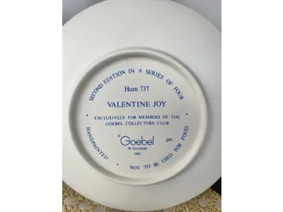 LOTE 052 - 01 RARO PRATO DE PORCELANA LINDAMENTE TRABALHADO DA FAMOSA M.J. HUMMEL GOEBEL APRESENTA UM FORMATO REDONDO E DESIGN MULTICOLORIDO, PERFEITO PARA TODAS AS OCASIÕES E ESTILOS DE DECORAÇÃO. É UM ITEM DE COLECIONADOR DA SEGUNDA EDIÇÃO DO PRATO VALENTINE JOY, GRAVADO COM DETALHES INTRINCADOS E FABRICADO NA ALEMANHA NA DÉCADA DE 1980.PEÇA ÚNICA DA CULTURA ALEMÃ E VEM DA FRANQUIA GOEBEL, UMA MARCA RENOMADA NO SETOR DE COLECIONÁVEIS ​​DECORATIVOS. LANÇADA SOMENTE PARA MEMBROS DO CLUBE DE COLECIONADORES GOEBEL. ITEM COMPRADO EM GARAGENS DE ANTIGUIDADES NOS EUA.SUPORTE PARA PRATO NÃO INCLUÍDO NESTA VENDA. (NO ESTADO) ATENÇÃO! FAZER A VISITAÇÃO ANTES DE ARREMATAR, NÃO SABEMOS SE FUNCIONA, LEILÃO NÃO TEM GARANTIA E NEM DEVOLUÇÃO, SUJEITO A POSSÍVEIS AVARIAS VISÍVEIS/OCULTAS E/OU AUSÊNCIA DE COMPONENTES.