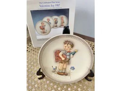 LOTE 052 - 01 RARO PRATO DE PORCELANA LINDAMENTE TRABALHADO DA FAMOSA M.J. HUMMEL GOEBEL APRESENTA UM FORMATO REDONDO E DESIGN MULTICOLORIDO, PERFEITO PARA TODAS AS OCASIÕES E ESTILOS DE DECORAÇÃO. É UM ITEM DE COLECIONADOR DA SEGUNDA EDIÇÃO DO PRATO VALENTINE JOY, GRAVADO COM DETALHES INTRINCADOS E FABRICADO NA ALEMANHA NA DÉCADA DE 1980.PEÇA ÚNICA DA CULTURA ALEMÃ E VEM DA FRANQUIA GOEBEL, UMA MARCA RENOMADA NO SETOR DE COLECIONÁVEIS ​​DECORATIVOS. LANÇADA SOMENTE PARA MEMBROS DO CLUBE DE COLECIONADORES GOEBEL. ITEM COMPRADO EM GARAGENS DE ANTIGUIDADES NOS EUA.SUPORTE PARA PRATO NÃO INCLUÍDO NESTA VENDA. (NO ESTADO) ATENÇÃO! FAZER A VISITAÇÃO ANTES DE ARREMATAR, NÃO SABEMOS SE FUNCIONA, LEILÃO NÃO TEM GARANTIA E NEM DEVOLUÇÃO, SUJEITO A POSSÍVEIS AVARIAS VISÍVEIS/OCULTAS E/OU AUSÊNCIA DE COMPONENTES.