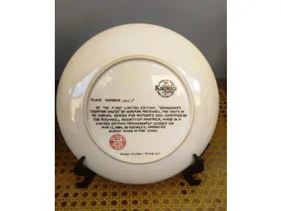 LOTE 250 - 01 NOSTÁLGICO PRATO DE NORMAN ROCKWELL  “VESTIDO DE CORTEJO DA VOVÓ” DE NORMAN ROCKWELL. VEM COM COA, PANFLETO, CAIXA ORIGINAL E CERTIFICADO DE AUTENTICIDADE. PRATO Nº 10111F. BRADEX 84-R70-2.9 O NONO DE UMA SÉRIE ANUAL PARA O DIA DAS MÃES. PRODUZIDO EM EDIÇÃO LIMITADA, PERMANENTEMENTE FECHADO EM 12 DE MAIO DE 1984. POR KNOWLES, O NOME MAIS ANTIGO DA AMÉRICA NA CHINA FINA. EM EXCELENTES CONDIÇÕES, SEM FALHAS VISÍVEIS, MANTIDO NA CAIXA ORIGINAL E NUNCA EXPOSTO. COM CAIXA NÃO ESTÁ PERFEITA E APRESENTA SINAIS DE ENVELHECIMENTO, FITA ADESIVA E A ETIQUETA DE REMESSA BRADFORD EXCHANGE. TAMANHO DA PLACA: 21,5 CM DE  DIÂMETRO.ITEM COMPRADO E GARAGENS DE ANTIGUIDADES NOS EUA. SUPORTE PARA PRATO NÃO INCLUÍDO NESTA VENDA. (NO ESTADO) ATENÇÃO! FAZER A VISITAÇÃO ANTES DE ARREMATAR, NÃO SABEMOS SE FUNCIONA, LEILÃO NÃO TEM GARANTIA E NEM DEVOLUÇÃO, SUJEITO A POSSÍVEIS AVARIAS VISÍVEIS/OCULTAS E/OU AUSÊNCIA DE COMPONENTES.