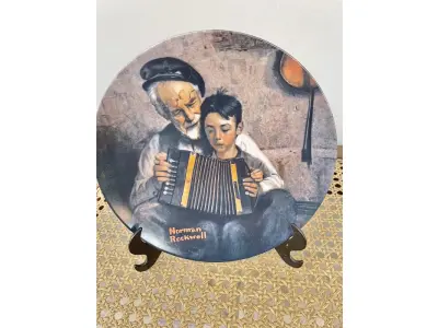 LOTE 210 - 01 RARO PRATO VINTAGE DE COLECIONADOR APRESENTA A ICÔNICA PINTURA DE NORMAN ROCKWELL, "THE MUSIC MAKER". COM 21 CM DE DIÂMETRO, E É FEITO DE PORCELANA. O PRATO FAZ PARTE DA FRANQUIA "KNOWLES" DE EDIÇÃO LIMITADA E PERTENCE À LINHA DE PRODUTOS "EARLY AMERICAN PRESCUT/EAPC".O PRATO É DECORADO COM UM PADRÃO RÚSTICO E APRESENTA UMA IMAGEM COLORIDA DE UM HOMEM TOCANDO UM INSTRUMENTO MUSICAL. FOI PRODUZIDO COM A TÉCNICA DE CERÂMICA E FABRICADO NOS ESTADOS UNIDOS NO FINAL DO SÉCULO XX (1970-1999). ESTE PRATO DECORATIVO É PERFEITO PARA TODAS AS OCASIÕES E SERIA UM ÓTIMO COMPLEMENTO PARA QUALQUER COLEÇÃO. NÚMERO DA PLACA: 20755I.COMPRADAS EM LOJAS DE ANTIGUIDADES DOS EUA.O SUPORTE DO PRATO NÃO ESTÁ INCLUÍDO.
