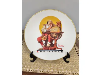 LOTE 224 - 01 BELO PRATO DE COLECIONADOR DE NORMAN ROCKWELL APRESENTA A EMOCIONANTE CENA DE "PLANEJANDO VISITAS DE NATAL" E É UM ITEM ESSENCIAL PARA QUALQUER COLEÇÃO. TEM BORDAS A OURO 24 K  COM 21,5 CM DE DIÂMETRO E É REPLETO DE DETALHES INTRINCADOS E CORES VIBRANTES QUE DÃO VIDA À CENA. O PRATO FOI FABRICADO NA DÉCADA DE 1970 PELA GORHAM, NOS ESTADOS UNIDOS. É UM ITEM VINTAGE E ESTÁ EM ÓTIMO ESTADO, PRONTO PARA SER EXIBIDO E APRECIADO POR MUITOS ANOS. ESTE SERIA UM PRESENTE PERFEITO PARA QUALQUER COLECIONADOR OU AMANTE DA OBRA DE NORMAN ROCKWELL.ITEM COMPRADO EM GARAGENS DE ANTIGUIDADES NOS EUA. SUPORTE PARA PRATO NÃO INCLUÍDO NESTA VENDA. (NO ESTADO) ATENÇÃO! FAZER A VISITAÇÃO ANTES DE ARREMATAR, NÃO SABEMOS SE FUNCIONA, LEILÃO NÃO TEM GARANTIA E NEM DEVOLUÇÃO, SUJEITO A POSSÍVEIS AVARIAS VISÍVEIS/OCULTAS E/OU AUSÊNCIA DE COMPONENTES.