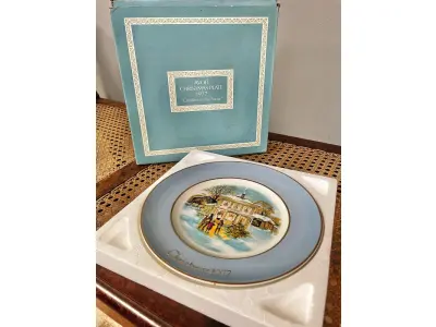 LOTE 030 - 01 LINDO PRATO DE NATAL DA SÉRIE AVON CHRISTMAS PLATE DE 1977, "CAROLLERS IN THE SNOW" - QUINTA EDIÇÃO DA SÉRIE. COM 22 CM DE DIÂMETRO E RETRATA UM GRUPO DE CANTORES DE NATAL EM FRENTE A UMA CASA DE DOIS ANDARES NO CENTRO. O VERSO MARCADO: SÉRIE DE PRATOS DE NATAL QUINTA EDIÇÃO "CANTORES DE NATAL NA NEVE" COM DOIS ANÉIS DE OURO 22K E O NATAL DE 1979 TAMBÉM EM OURO 22K.  FEITO EXCLUSIVAMENTE PARA A AVON CTS INC., 1977 POR ENOCH WEDGWOOD (TUNSTALL) LTD., INGLATERRA PEÇA COMPRADA EM GARAGEM DE ANTIGUIDADES NOS EUA. SUPORTE PARA PRATO NÃO INCLUÍDO NESTA VENDA. (NO ESTADO) ATENÇÃO! FAZER A VISITAÇÃO ANTES DE ARREMATAR, NÃO SABEMOS SE FUNCIONA, LEILÃO NÃO TEM GARANTIA E NEM DEVOLUÇÃO, SUJEITO A POSSÍVEIS AVARIAS VISÍVEIS/OCULTAS E/OU AUSÊNCIA DE COMPONENTES.