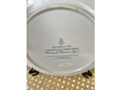 LOTE 058 - 01 PRATO DE NATAL COLECIONÁVEL DA AVON CHRISTMAS MEMORIAS DE 1981, O PRIMEIRO DA SÉRIE. COMPRANDO EM LOJA DE ANTIGUIDADES NO JAPÃO. COM ACABAMENTO EM OURO 22K, APRESENTA UMA MARAVILHOSA CENA VINTAGE DE UM MENINO E UMA MENINA LEVANDO A ÁRVORE E AS PLANTAS PARA CASA PARA AS FESTAS DE FIM DE ANO. CORES E DETALHES LINDOS. EM ÓTIMO ESTADO, COM LEVE DESGASTE NA BORDA INFERIOR DO PRATO E LEVES ARRANHÕES. COM CAIXA. TEM 23 CM DE DIÂMETRO.SUPORTE PARA PRATO NÃO INCLUÍDO NESTA VENDA. (NO ESTADO) ATENÇÃO! FAZER A VISITAÇÃO ANTES DE ARREMATAR, NÃO SABEMOS SE FUNCIONA, LEILÃO NÃO TEM GARANTIA E NEM DEVOLUÇÃO, SUJEITO A POSSÍVEIS AVARIAS VISÍVEIS/OCULTAS E/OU AUSÊNCIA DE COMPONENTES.