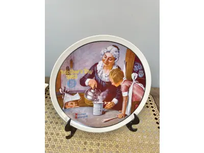 01 PRATO DE NORMAN ROCKWELL PARA O DIA DAS MÃES DE 1982, "THE COOKING LESSON", DA PORCELANA FINA KNOWLES. O NÚMERO DO PRATO É 13025N , DA PRIMEIRA EDIÇÃO LIMITADA. O SÉTIMO DE UMA SÉRIE ANUAL PARA O DIA DAS MÃES. CERTIFICADO PELA ROCKWELL SOCIETY OF AMERICA. ESTE PRATO É UMA EDIÇÃO LIMITADA, PERMANENTEMENTE FECHADA, FEITA EM 7 DE MAIO DE 1982 PELA KNOWLES, A MARCA MAIS ANTIGA DA AMÉRICA EM PORCELANA FINA. O PRATO MEDE 21,8 CM DE DIÂMETRO E ESTÁ EM ÓTIMO ESTADO ITEM COMPRADO EM 2/10/1982 COM CERTIFICADO DE AUTENTICIDADE NOTAS E DOCUMENTOS DE COMPRA.  ITEM COMPRADO EM GARAGENS DE ANTIGUIDADES NOS EUA.SUPORTE PARA PRATO NÃO INCLUÍDO NESTA VENDA. (NO ESTADO) ATENÇÃO! FAZER A VISITAÇÃO ANTES DE ARREMATAR, NÃO SABEMOS SE FUNCIONA, LEILÃO NÃO TEM GARANTIA E NEM DEVOLUÇÃO, SUJEITO A POSSÍVEIS AVARIAS VISÍVEIS/OCULTAS E/OU AUSÊNCIA DE COMPONENTES.