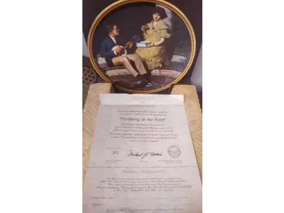 LOTE 125 - 01 PRATO DE NORMAN ROCKWELL EDIÇÃO LIMITADA "A 100 DIAS DE QUEIMA DE ESTOQUE" DA SÉRIE MULHERES REDESCOBERTAS, "PONDERING ON THE PORCH"3º PRATO DA SÉRIE MULHERES REDESCOBERTAS,21,5 CM DE DIÂMETRO, BRADEX Nº 84-R70-4.3 1981 EDWIN M. KNOWLES CHINA COMPANY UM GENUÍNO CLÁSSICO ROCKWELL. FINA EDWIN M KNOWLES. COM CERTIFICADO DE AUTENTICIDADE, FEITO NOS ESTADOS UNIDOS. PERFEITO PARA FÃS DA ICÔNICA OBRA DE ROCKWELL, ESTE PRATO DE COLECIONADOR É UM ITEM ESSENCIAL PARA QUALQUER COLEÇÃO. ADICIONE ESTA PEÇA DESLUMBRANTE À SUA COLEÇÃO HOJE MESMO E ADMIRE OS DETALHES COMPLEXOS E AS BELAS CORES QUE FAZEM DESTE PRATO UMA OBRA DE ARTE. COM CERTIFICADO DE AUTENTICIDADE. ITEM COMPRADO E GARAGENS DE ANTIGUIDADES NOS EUA.SUPORTE PARA PRATO NÃO INCLUÍDO NESTA VENDA. (NO ESTADO) ATENÇÃO! FAZER A VISITAÇÃO ANTES DE ARREMATAR, NÃO SABEMOS SE FUNCIONA, LEILÃO NÃO TEM GARANTIA E NEM DEVOLUÇÃO, SUJEITO A POSSÍVEIS AVARIAS VISÍVEIS/OCULTAS E/OU AUSÊNCIA DE COMPONENTES.