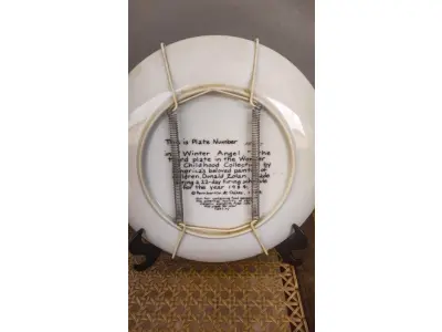 LOTE 187 - 01 RARO PRATO DE COLECIONADOR... INTITULADA "ANJO DO INVERNO"... ESTA É A PLACA NÚMERO 1592J... TERCEIRA PLACA DA COLEÇÃO MARAVILHAS DA INFÂNCIA DO AMADO PINTOR INFANTIL AMERICANO, DONALD ZOLAN  FEITA DURANTE UM PERÍODO DE QUEIMA DE 22 DIAS NO ANO DE 1984. COM DIREITOS AUTORAIS DE PEMBERTON & OAKES, 1984. COM CAIXA FOLHETO E  CERTIFICADO DE AUTENTICIDADE (COA) INCLUSOS NESTE ITEM. MEDE APROXIMADAMENTE 21 CM DE DIÂMETRO.COMPRADAS EM LOJAS DE ANTIGUIDADES DOS EUA.O SUPORTE DO PRATO NÃO ESTÁ INCLUÍDO. (NO ESTADO) ATENÇÃO! FAZER A VISITAÇÃO ANTES DE ARREMATAR, NÃO SABEMOS SE FUNCIONA, LEILÃO NÃO TEM GARANTIA E NEM DEVOLUÇÃO, SUJEITO A POSSÍVEIS AVARIAS VISÍVEIS/OCULTAS E/OU AUSÊNCIA DE COMPONENTES.