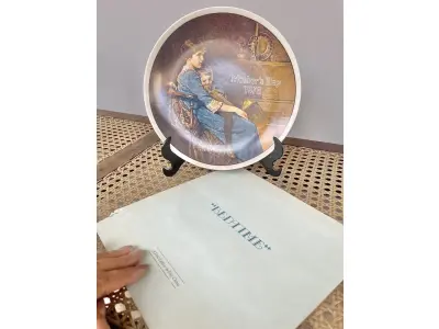 LOTE 129 - 01 PRATO NORMAN ROCKWELL PARA O DIA DAS MÃES – HORA DE DORMIR, 1978. ESTE SERIA UM ÓTIMO PRESENTE PARA QUALQUER PESSOA NASCIDA EM 1978 OU PARA TODAS AS MÃES, PRATO DE PORCELANA FINA DA SÉRIE LIMITADA FECHADA PERMANENTEMENTE EM 28 DE ABRIL DE 1978 POR KNOWLES "BEDTIME", DEDICADA AO DIA DAS MÃES, COMPRADO NOVO NA THE BRADFORD EXCHANGE EM 1978 E FABRICADO PELA KNOWLES FINE CHINA. A IMAGEM FOI CRIADA PELO ARTISTA NORMAN ROCKWELL E É CERTIFICADA PELA ROCKWELL SOCIETY OFF AMÉRICA. OS PRATOS DA SÉRIE "DIA DAS MÃES" ERAM LANÇADOS ANUALMENTE E EXIBIAM O ANO DE EMISSÃO E A PALAVRA "DIA DAS MÃES" DECORATIVAMENTE GRAVADA EM CADA FACE DO PRATO. ITEM COMPRADO EM GARAGEM DE ANTIGUIDADES NOS EUA OBSERVAÇÃO: O SUPORTE DE MOSTRADO NAS FOTOS NÃO ESTÁ INCLUÍDO. (NO ESTADO) ATENÇÃO! FAZER A VISITAÇÃO ANTES DE ARREMATAR, NÃO SABEMOS SE FUNCIONA, LEILÃO NÃO TEM GARANTIA E NEM DEVOLUÇÃO, SUJEITO A POSSÍVEIS AVARIAS VISÍVEIS/OCULTAS E/OU AUSÊNCIA DE COMPONENTES.