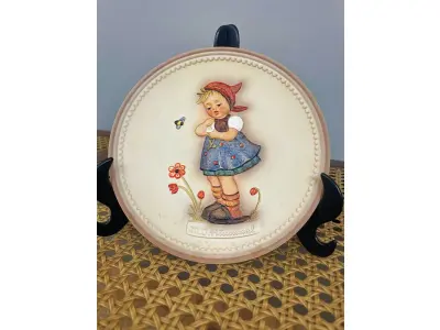 LOTE 313 - 01 RARO PRATO DE PORCELANA LINDAMENTE TRABALHADO DA FAMOSA M.J. HUMMEL GOEBEL APRESENTA UM FORMATO REDONDO E DESIGN MULTICOLORIDO, PERFEITO PARA TODAS AS OCASIÕES E ESTILOS DE DECORAÇÃO. É UM ITEM DE COLECIONADOR DA SEGUNDA EDIÇÃO DO PRATO VALENTINE JOY, GRAVADO COM DETALHES INTRINCADOS E FABRICADO NA ALEMANHA NA DÉCADA DE 1980.TERCEIRA EDIÇÃO DE UMA SÉRIE DE QUATRO PRATOS LANÇADOS PEÇA ÚNICA DA CULTURA ALEMÃ E VEM DA FRANQUIA GOEBEL, COM 16 CM DE DIÂMETROUMA MARCA RENOMADA NO SETOR DE COLECIONÁVEIS ​​DECORATIVOS. LANÇADA SOMENTE PARA MEMBROS DO CLUBE DE COLECIONADORES GOEBEL. ITEM COMPRADO EM GARAGENS DE ANTIGUIDADES NOS EUA.SUPORTE PARA PRATO NÃO INCLUÍDO NESTA VENDA. (NO ESTADO) ATENÇÃO! FAZER A VISITAÇÃO ANTES DE ARREMATAR, NÃO SABEMOS SE FUNCIONA, LEILÃO NÃO TEM GARANTIA E NEM DEVOLUÇÃO, SUJEITO A POSSÍVEIS AVARIAS VISÍVEIS/OCULTAS E/OU AUSÊNCIA DE COMPONENTES.