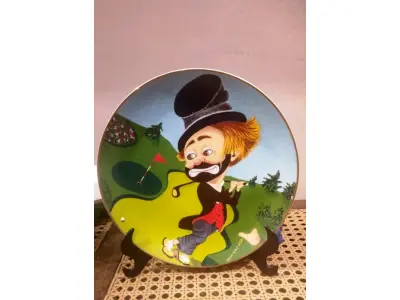LOTE 268 - 01 RARO PRATO DE COLECIONADOR DE EDIÇÃO LIMITADA APRESENTA O ICÔNICO PERSONAGEM RED SKELETON, "ASSINADO À MÃO" FREDDIE, JOGANDO GOLFE "FREDDIE ON THE GREEN"  COM 21 CM DE DIÂMETRO, PEÇA  VINTAGE FOI FABRICADA NOS ESTADOS UNIDOS DURANTE A DÉCADA DE 1980 E ESTÁ EM EXCELENTES CONDIÇÕES. PERFEITA PARA QUALQUER ENTUSIASTA DO RED SKELETON, ITEM DE COLECIONADOR, ESTA PEÇA DECORATIVA ADICIONARÁ UM TOQUE DE HUMOR E NOSTALGIA A QUALQUER COLEÇÃO.  ITEM ÚNICO E DIFÍCIL DE ENCONTRAR, UNICO NOBRASIL APENAS 10 MIL PRATOS LANÇADOS NOS EUA. PRATO DE Nº 3597/10.000. ITEM COMPRADO EM GARAGEM DE ANTIGUIDADES NOS EUA. SUPORTE PARA PRATO NÃO INCLUÍDO NESTA VENDA. (NO ESTADO) ATENÇÃO! FAZER A VISITAÇÃO ANTES DE ARREMATAR, NÃO SABEMOS SE FUNCIONA, LEILÃO NÃO TEM GARANTIA E NEM DEVOLUÇÃO, SUJEITO A POSSÍVEIS AVARIAS VISÍVEIS/OCULTAS E/OU AUSÊNCIA DE COMPONENTES.