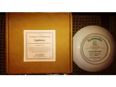 LOTE 310 - 01 PRATO DE COLECIONADOR SUNBEAM BESSIE PEASE GUTMAN CAMEO PORTRAIT ASSINADO E NUMERADO, ESTE PRATO VINTAGE DE COLECIONADOR GOLDILOCKS DE 1986, DA COLEÇÃO HAMILTON, É UM ITEM ESSENCIAL PARA QUALQUER COLECIONADOR DE CULTURA AMERICANA. É A 4ª EDIÇÃO DA PRECIOUS PORTRAITS E TEM O NÚMERO AUTÊNTICO 4317P.FEITO DE PORCELANA DE ALTA QUALIDADE, ESTE PRATO APRESENTA UMA BELA E VIBRANTE IMAGEM MULTICOLORIDA DE UMA JOVEM QUE ADICIONARÁ UM TOQUE DE ELEGÂNCIA A QUALQUER COLEÇÃO DECORATIVA.EM EXCELENTE ESTADO, POSSUI A CAIXA ORIGINAL E OS DOCUMENTOS. O SUPORTE DO PRATO NÃO ESTÁ INCLUÍDO. PEÇA COMPRADA EM GARAGEM DE ANTIGUIDADES NOS EUA. SUPORTE PARA PRATO NÃO INCLUÍDO NESTA VENDA. (NO ESTADO) ATENÇÃO! FAZER A VISITAÇÃO ANTES DE ARREMATAR, NÃO SABEMOS SE FUNCIONA, LEILÃO NÃO TEM GARANTIA E NEM DEVOLUÇÃO, SUJEITO A POSSÍVEIS AVARIAS VISÍVEIS/OCULTAS E/OU AUSÊNCIA DE COMPONENTES.