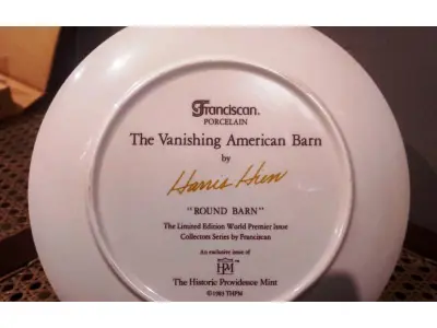 LOTE 316 - 01 RARO PRATO PORCELANA DA COLEÇÃO CELEIROS AMERICANOS EM EXTINÇÃO FRANCISCANA DA HISTORIC PROVIDENCE MINT WORLD PREMIER FIRST EDITION, DE 1983, DA SÉRIE THE VANISHING AMERICAN BARN, DA HARRIS HIEN, A SEGUNDA EDIÇÃO DA SÉRIE, INTITULADA "ROUND  BARN". EM PORTUGUES “CELEIRO REDONDO” O PRATO APRESENTA UMA REPRESENTAÇÃO ÚNICA, DETALHADA E COLORIDA DE UM TIPO DE CELEIRO AMERICANO, SITUADO EM UM CENÁRIO DE FAZENDA DE DIFERENTES REGIÕES DO PAÍS, COM DETALHES DOURADOS NA BORDA. ESTAMPADAS NA PARTE INFERIOR COM O NOME DA SÉRIE, TÍTULO, ASSINATURA IMPRESSA DO ARTISTA E A MARCA THE HISTORIC PROVIDENCE MINT, E MEDEM APROXIMADAMENTE 21,8 CM DE DIÂMETRO. EM EXCELENTE ESTADO, POSSUI A CAIXA ORIGINAL E OS DOCUMENTOS. O SUPORTE DO PRATO NÃO ESTÁ INCLUÍDO. PEÇA COMPRADA EM GARAGEM DE ANTIGUIDADES NOS EUA. SUPORTE PARA PRATO NÃO INCLUÍDO NESTA VENDA. (NO ESTADO) ATENÇÃO! FAZER A VISITAÇÃO ANTES DE ARREMATAR, NÃO SABEMOS SE FUNCIONA, LEILÃO NÃO TEM GARANTIA E NEM DEVOLUÇÃO, SUJEITO A POSSÍVEIS AVARIAS VISÍVEIS/OCULTAS E/OU AUSÊNCIA DE COMPONENTES.