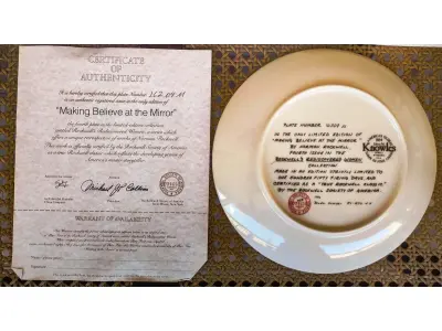 LOTE 147 - 01 RARO PRATO PARA AMANTES E COLECIONADORES DE NORMAN ROCKWELL! ESTE É UM PRATO COLECIONÁVEL DE PORCELANA VINTAGE DE EDIÇÃO LIMITADA. "MAKING BELIEVE AT THE MIRROR" DE NUMERO 16209M É A QUARTA PLACA DA COLEÇÃO DE EDIÇÃO LIMITADA INTITULADA ROCKWELL'S REDISCOVERED WOMEN, UMA SÉRIE QUE OFERECE UMA RETROSPECTIVA ÚNICA DAS OBRAS DE NORMAN ROCKWELL. ESTA OBRA É OFICIALMENTE CERTIFICADA PELA ROCKWELL SOCIETY OF AMERICA. FOI ENCONTRADA EM UM ARMÁRIO DURANTE A VENDA DE UMA PROPRIEDADE, APÓS MUITOS ANOS GUARDADA.  CAIXA ORIGINAL E CERTIFICADO DE AUTENTICIDADE DA PEÇA  O PRATO MEDE 21,5 CM DE DIÂMETRO.  SUPORTE PARA PRATO NÃO INCLUÍDO NESTA VENDA. (NO ESTADO) ATENÇÃO! FAZER A VISITAÇÃO ANTES DE ARREMATAR, NÃO SABEMOS SE FUNCIONA, LEILÃO NÃO TEM GARANTIA E NEM DEVOLUÇÃO, SUJEITO A POSSÍVEIS AVARIAS VISÍVEIS/OCULTAS E/OU AUSÊNCIA DE COMPONENTES.