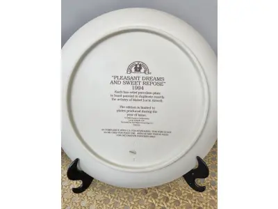 LOTE 133 - 01 LINDO PRATO ENESCO BAS RELIEF DE 1994 DA COLEÇÃO MABEL LUCIE ATWELL EM BAIXO RELEVO PINTADO A MÃO, EDIÇÃO LIMITADA, COM UM TEMA "PLEASANT DREAMS AND SWEET REPOSE"," SONHOS AGRADAVEIS" DESIGN MULTICOLORIDO E PADRÃO DECORATIVO. FEITO DE CERÂMICA NA INDONÉSIA, COM 21,5 CM DE DIÂMETRO  PEÇA VINTAGE DO FINAL DO SÉCULO XX. A MARCA ENESCO É CONHECIDA POR SEUS PRATOS DE COLECIONADOR, E ESTE ITEM EM PARTICULAR FAZ PARTE DA FRANQUIA MABEL LUCIE ATWELL, ITEM RARO COM TODOS OS DOCUMENTOS, COMPRADO EM GARAGEM DE ANTIGUIDADES NOS EUA.SUPORTE PARA PRATO NÃO INCLUÍDO NESTA VENDA. (NO ESTADO) ATENÇÃO! FAZER A VISITAÇÃO ANTES DE ARREMATAR, NÃO SABEMOS SE FUNCIONA, LEILÃO NÃO TEM GARANTIA E NEM DEVOLUÇÃO, SUJEITO A POSSÍVEIS AVARIAS VISÍVEIS/OCULTAS E/OU AUSÊNCIA DE COMPONENTES.