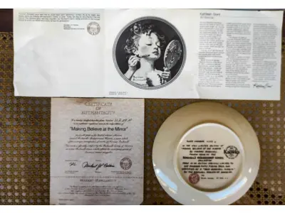 LOTE 147 - 01 RARO PRATO PARA AMANTES E COLECIONADORES DE NORMAN ROCKWELL! ESTE É UM PRATO COLECIONÁVEL DE PORCELANA VINTAGE DE EDIÇÃO LIMITADA. "MAKING BELIEVE AT THE MIRROR" DE NUMERO 16209M É A QUARTA PLACA DA COLEÇÃO DE EDIÇÃO LIMITADA INTITULADA ROCKWELL'S REDISCOVERED WOMEN, UMA SÉRIE QUE OFERECE UMA RETROSPECTIVA ÚNICA DAS OBRAS DE NORMAN ROCKWELL. ESTA OBRA É OFICIALMENTE CERTIFICADA PELA ROCKWELL SOCIETY OF AMERICA. FOI ENCONTRADA EM UM ARMÁRIO DURANTE A VENDA DE UMA PROPRIEDADE, APÓS MUITOS ANOS GUARDADA.  CAIXA ORIGINAL E CERTIFICADO DE AUTENTICIDADE DA PEÇA  O PRATO MEDE 21,5 CM DE DIÂMETRO.  SUPORTE PARA PRATO NÃO INCLUÍDO NESTA VENDA. (NO ESTADO) ATENÇÃO! FAZER A VISITAÇÃO ANTES DE ARREMATAR, NÃO SABEMOS SE FUNCIONA, LEILÃO NÃO TEM GARANTIA E NEM DEVOLUÇÃO, SUJEITO A POSSÍVEIS AVARIAS VISÍVEIS/OCULTAS E/OU AUSÊNCIA DE COMPONENTES.