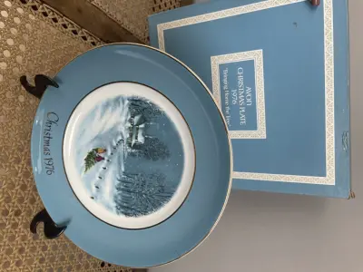 LOTE 299 - 01 LINDO PRATO DE NATAL DA SÉRIE AVON CHRISTMAS PLATE DE 1976, " BRINGING HOME THE TREE" - TERCEIRA  EDIÇÃO DA SÉRIE. COM 22 CM DE DIÂMETRO E RETRATA UM GRUPO DE PESSOAS PATINANDO NA NEVE . O VERSO MARCADO COM DOIS ANÉIS DE OURO 22K.FEITO EXCLUSIVAMENTE PARA A AVON CTS INC., 1976 POR ENOCH WEDGWOOD (TUNSTALL) LTD, INGLATERRA.PEÇA COMPRADA EM GARAGEM DE ANTIGUIDADES NOS EUA. SUPORTE PARA PRATO NÃO INCLUÍDO NESTA VENDA. (NO ESTADO) ATENÇÃO! FAZER A VISITAÇÃO ANTES DE ARREMATAR, NÃO SABEMOS SE FUNCIONA, LEILÃO NÃO TEM GARANTIA E NEM DEVOLUÇÃO, SUJEITO A POSSÍVEIS AVARIAS VISÍVEIS/OCULTAS E/OU AUSÊNCIA DE COMPONENTES.