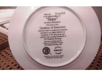 LOTE 291 - 01PRATO IMPECÁVEL E RARO IMPECÁVEL GARDENS OF INNOCENCE DONNA RICHARDSON HOPE É A EDIÇÃO 1 DA SÉRIE DE 8 PLACAS PARA COLECIONADORES, GARDEN OF INNOCENCE, DE DONNA RICHARDSON PARA A BRADFORD EXCHANGE DE 1993. ESTA SÉRIE, GARDEN OF INNOCENCE, REÚNE CRIANÇAS ANGELICAIS EM UM CENÁRIO DE JARDIM ONÍRICO. CADA PLACA POSSUI UMA BORDA TRIPLA DE TAPEÇARIA E DESIGN EM ÔNIX. PEÇA VINTAGE COLACIONÁVEL 2ª EDIÇÃO BRADFORD EXCHANGE. SAFRA 1993. EDIÇÃO LIMITADA. PLACA NUMERADA. .COM 20 CM DE DIÂMETRO COM UMA FAIXA EM OURO 22K, HOPE TEM DURAÇÃO LIMITADA A 95 DIAS DE QUEIMA DE ESTOQUE E LOGO FOI FECHADA A FABRICAÇÃO DA MESMA. NA EMBALAGEM ORIGINAL DE ISOPOR COM CERTIFICADO E FOLHETO DA ÉPOCA. (NO ESTADO) ATENÇÃO! FAZER A VISITAÇÃO ANTES DE ARREMATAR, NÃO SABEMOS SE FUNCIONA, LEILÃO NÃO TEM GARANTIA E NEM DEVOLUÇÃO, SUJEITO A POSSÍVEIS AVARIAS VISÍVEIS/OCULTAS E/OU AUSÊNCIA DE COMPONENTES.