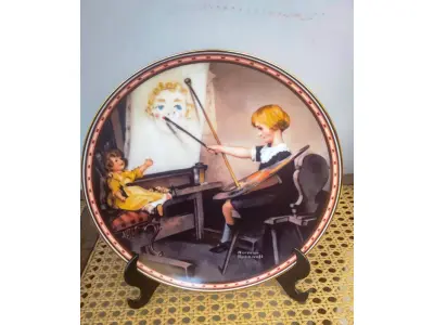 LOTE 279 - 01 LINDO PRATO COLECIONÁVEL VINTAGE DE NORMAN ROCKWELL. A SEGUNDA EDIÇÃO DE "A MIND OF HER OWN ROCKWELL'S STUDIES OF GIRLHOOD". - "SERIOUS BUSINESS" -  A CENA CAPTURA UMA JOVEM ARTISTA PINTANDO UM QUADRO. A ARTE NESTA PLACA FOI SELECIONADA E APROVADA PARA INCLUSÃO NESTA SÉRIE DE PLACAS PELO NORMAN ROCKWELL FAMILY TRUST, RECEBENDO SEU SELO DE ENDOSSO E AUTENTICAÇÃO. PINTADA POR NORMAN ROCKWELL EM 1922 E AGORA PRESERVADA EM PORCELANA FINA KNOWLES EM UMA EDIÇÃO ESTRITAMENTE LIMITADA A 150 DIAS DE QUEIMA. CERTIFICADA COMO UM VERDADEIRO CLÁSSICO ROCKWELL PELA ROCKWELL SOCIETY OF AMERICA. ESTA É OBVIAMENTE UMA JOVEM MUITO DETERMINADA. MEU PAI RESPEITAVA ESSA QUALIDADE. THOMAS ROKWELL BRADEX Nº 84-R70-9.2, PLACA NUMERADA 5662D, ILUSTRAÇÃO LINDAMENTE DETALHADA DE NORMAN ROCKWELL, PERFEITO PARA COLECIONADORES OU COMO PRESENTE,  IDEAL PARA EXIBIÇÃO EM PAREDE OU PRATELEIRA, ENRIQUEÇA SUA DECORAÇÃO OU COMECE UMA COLEÇÃO DE ARTE COM ESTA PEÇA ATEMPORAL. COM 21 CM DE DIAMETRO CAIXA E CERTIFICADO E FOLHETOS  ORIGINAIS.PEÇA COMPRADA EM GARAGEM DE ANTIGUIDADES NOS EUA. SUPORTE PARA PRATO NÃO INCLUÍDO NESTA VENDA. (NO ESTADO) ATENÇÃO! FAZER A VISITAÇÃO ANTES DE ARREMATAR, NÃO SABEMOS SE FUNCIONA, LEILÃO NÃO TEM GARANTIA E NEM DEVOLUÇÃO, SUJEITO A POSSÍVEIS AVARIAS VISÍVEIS/OCULTAS E/OU AUSÊNCIA DE COMPONENTES.