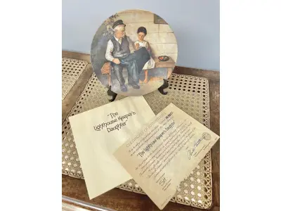 LOTE 131 - 01 PRATO NORMAN ROCKWELL.UM PEDAÇO DA HISTÓRIA AMERICANA COM ESTE PRATO DE COLECIONADOR DE  EDIÇÃO LIMITADA, COM UMA BELA ILUSTRAÇÃO DE NORMAN ROCKWELL DE 1979. ESTE PRATO RETRATA LIGHTHOUSE KEEPER’S DAUGHTER "A FILHA DO FAROLEIRO" E É FEITO NOS ESTADOS UNIDOS. PERFEITO PARA FÃS DA ICÔNICA OBRA DE ROCKWELL, ESTE PRATO DE COLECIONADOR É UM ITEM ESSENCIAL PARA QUALQUER COLEÇÃO. ADICIONE ESTA PEÇA DESLUMBRANTE À SUA COLEÇÃO HOJE MESMO E ADMIRE OS DETALHES COMPLEXOS E AS BELAS CORES QUE FAZEM DESTE PRATO UMA OBRA DE ARTE. COM CERTIFICADO DE AUTENTICIDADE. ITEM COMPRADO E GARAGENS DE ANTIGUIDADES NOS EUA. SUPORTE PARA PRATO NÃO INCLUÍDO NESTA VENDA. (NO ESTADO) ATENÇÃO! FAZER A VISITAÇÃO ANTES DE ARREMATAR, NÃO SABEMOS SE FUNCIONA, LEILÃO NÃO TEM GARANTIA E NEM DEVOLUÇÃO, SUJEITO A POSSÍVEIS AVARIAS VISÍVEIS/OCULTAS E/OU AUSÊNCIA DE COMPONENTES.