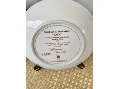 LOTE 159 - 01 PRATO COLECIONÁVEL "AMY" DE MARILYN ZAPP, DE 1983, DA BRENTWOOD FINE ARTS. ESTE PRATO FOI CRIADO A PARTIR DE UMA OBRA DE ARTE ORIGINAL DE MARILYN ZAPP. EDIÇÃO NUMERADA, 2873 EXEMPLARES/12.500 SENDO LANÇADAS APENAS 10 MIL EXEMPLARES NOS EUA E 25,00EXEMPLARES LAÇADOS NO CANADA NA DÉCADA DE 80. MEDE 21,8 CM DE DIÂMETRO.  ITEM COMPRADO EM GARAGENS DE ANTIGUIDADES NOS EUA. SUPORTE PARA PRATO NÃO INCLUÍDO NESTA VENDA. (NO ESTADO) ATENÇÃO! FAZER A VISITAÇÃO ANTES DE ARREMATAR, NÃO SABEMOS SE FUNCIONA, LEILÃO NÃO TEM GARANTIA E NEM DEVOLUÇÃO, SUJEITO A POSSÍVEIS AVARIAS VISÍVEIS/OCULTAS E/OU AUSÊNCIA DE COMPONENTES.