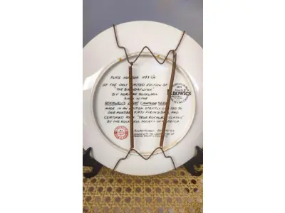 LOTE 195 - 01 PRATO DE COLECIONADOR DE EDIÇÃO LIMITADA APRESENTA A ICÔNICA OBRA DE ARTE DE NORMAN ROCKWELL INTITULADA "THE BIRTHDAY WISH". O PRATO É FEITO DE PORCELANA E TEM 21,5 CM DE DIÂMETRO COM BORDA DOURADA. ACOMPANHA CAIXA ORIGINAL, FOLHETO E CERTIFICADO DE AUTENTICIDADE E NOTA DE COMPRA E DATADA EM 10/16/1984, TORNANDO-SE UM ÓTIMO COMPLEMENTO PARA QUALQUER COLEÇÃO. O PRATO FOI FABRICADO NOS ESTADOS UNIDOS NA DÉCADA DE 1980 E É CONSIDERADO UM ITEM VINTAGE. ALÉM DE SUA IMPORTÂNCIA CULTURAL COMO ITEM COLECIONÁVEL AMERICANO, ESTE PRATO TAMBÉM OSTENTA DIVERSAS CARACTERÍSTICAS, INCLUINDO O STATUS DE EDIÇÃO LIMITADA E A INCLUSÃO DA EMBALAGEM E DOCUMENTAÇÃO ORIGINAIS. É PERFEITO PARA QUALQUER OCASIÃO E UM ÓTIMO PRESENTE PARA QUALQUER COLECIONADOR OU ENTUSIASTA.COMPRADAS EM LOJAS DE ANTIGUIDADES DOS EUA.O SUPORTE DO PRATO NÃO ESTÁ INCLUÍDO. (NO ESTADO) ATENÇÃO! FAZER A VISITAÇÃO ANTES DE ARREMATAR, NÃO SABEMOS SE FUNCIONA, LEILÃO NÃO TEM GARANTIA E NEM DEVOLUÇÃO, SUJEITO A POSSÍVEIS AVARIAS VISÍVEIS/OCULTAS E/OU AUSÊNCIA DE COMPONENTES.