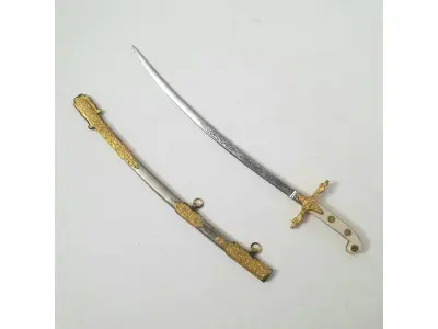 LOTE 115 - 01 MINIATURA DE ESPADA DA MARINHA EM METAL. LÂMINA CINZELADA DE  DUQUE DE CAIXAS  RJ. DA DECADA DE 80 BAINHA DE METAL COM APLIQUES EM METAL DOURADO,COM 15 CM DE CUMPRIMENTO. (NO ESTADO) ATENÇÃO! FAZER A VISITAÇÃO ANTES DE ARREMATAR, NÃO SABEMOS SE FUNCIONA, LEILÃO NÃO TEM GARANTIA E NEM DEVOLUÇÃO, SUJEITO A POSSÍVEIS AVARIAS VISÍVEIS/OCULTAS E/OU AUSÊNCIA DE COMPONENTES.