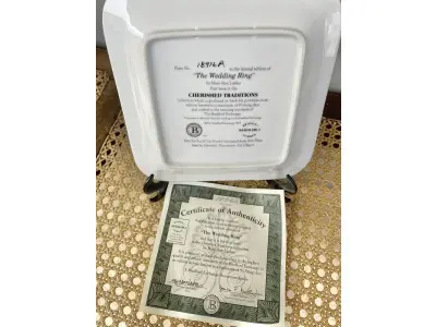 LOTE 114 - 01 PRATO DE COLEÇÃO DA COLCHA CHERISHED TRADITIONS THE WEDDING RING "ALIANÇA DE CASAMENTO" MARY ANN LASHER 1º DA SÉRIE COM 17,5 CM DE DIÂMETRO,EDIÇÃO LIMITADA, DESENHADO POR MARY ANN LASHER. UMA ALEGRE ALIANÇA DUPLA ENVOLVE UM BUQUÊ COLORIDO DE FLORES NESTE DESIGN DE PORCELANA. UMA EDIÇÃO ESTRITAMENTE LIMITADA A 150 DIAS DE QUEIMA NOS EUA. ITEM FOI ENCONTRADO EM UM ARMÁRIO DURANTE A VENDA DE UMA PROPRIEDADE NOS EUA APÓS MUITOS ANOS GUARDADOS.  CAIXA “ORIGINAL E COM CERTIFICADO DE AUTENTICIDADE,SUPORTE PARA PRATO NÃO INCLUÍDO NESTA VENDA. (NO ESTADO) ATENÇÃO! FAZER A VISITAÇÃO ANTES DE ARREMATAR, NÃO SABEMOS SE FUNCIONA, LEILÃO NÃO TEM GARANTIA E NEM DEVOLUÇÃO, SUJEITO A POSSÍVEIS AVARIAS VISÍVEIS/OCULTAS E/OU AUSÊNCIA DE COMPONENTES.