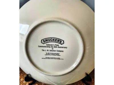 LOTE 157 - 01 LINDO PRATO DE NATAL DA SMUCKER'S COM 21 ,5 FAZIA PARTE DE UMA SÉRIE PARA COLECIONADORES E ERA INCLUÍDO EM UM PACOTE ANUAL DE PRESENTES DE NATAL CONTENDO UMA VARIEDADE DE GELEIAS E COMPOTAS DA SMUCKER'S. DAVID PROJETOU SEU PRIMEIRO PRATO PARA A SMUCKER'S EM 1972, COM OS PRIMEIROS DEZ PRATOS APRESENTANDO CENAS NATALINAS DE TODOS OS LUGARES, INCLUINDO A WILLIAMSBURG COLONIAL, A FILADÉLFIA HISTÓRICA, O VALE DO MISSISSIPPI E ATÉ MESMO A SUÍÇA. NO ENTANTO, A PARTIR DE 1982, A ARTE DE DAVID PARA A SÉRIE DE PRATOS RETRATAVA PRÉDIOS HISTÓRICOS E CENÁRIOS RURAIS DURANTE A TEMPORADA DE FÉRIAS EM TODO O ESTADO DE OHIO, SEDE DA SMUCKER COMPANY. AO LONGO DOS ANOS, MUITOS PRATOS DE NATAL CAPTURARAM A AUTENTICIDADE E O ESPÍRITO NATALINO DA COMUNIDADE DA SMUCKER'S, APRESENTANDO LOCAIS DENTRO E AO REDOR DA CIDADE DE ORRVILLE, SEDE DA EMPRESA, E OUTRAS PARTES DO CONDADO DE WAYNE. APÓS CINQUENTA ANOS, DAVID COMPLETOU ESTA SÉRIE COM UM PRATO FINAL PRODUZIDO EM 2021.  ITEM COMPRADO EM GARAGENS DE ANTIGUIDADES NOS EUA. SUPORTE PARA PRATO NÃO INCLUÍDO NESTA VENDA. (NO ESTADO) ATENÇÃO! FAZER A VISITAÇÃO ANTES DE ARREMATAR, NÃO SABEMOS SE FUNCIONA, LEILÃO NÃO TEM GARANTIA E NEM DEVOLUÇÃO, SUJEITO A POSSÍVEIS AVARIAS VISÍVEIS/OCULTAS E/OU AUSÊNCIA DE COMPONENTES.