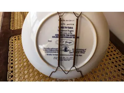LOTE 343 - 01  PRATO DE COLECIONADOR "E O VENTO LEVOU" DE 1989, "THE HOME TO TARA", É UMA ADIÇÃO DESLUMBRANTE À COLEÇÃO DE QUALQUER COLECIONADOR. APRESENTANDO A ICÔNICA MANSÃO DO ADORADO FILME, ESTE PRATO CAPTURA A GRANDIOSIDADE E A BELEZA DE "E O VENTO LEVOU". FABRICADO EM 1989, ESTE ITEM DE COLECIONADOR É ESSENCIAL PARA OS FÃS DO CLÁSSICO. COM DETALHES MINUCIOSOS E ACABAMENTO PRIMOROSO, ESTE PRATO É A MANEIRA PERFEITA DE COMEMORAR A HISTÓRIA ATEMPORAL DE SCARLETT O'HARA E RHETT BUTLER. QUINTA EDIÇÃO DA SÉRIE BODAS DE OURO DE 1989, OFICIALMENTE AUTORIZADA PELA METRO-GOLDWYN-MAYER PARA COMEMORAR O 50º ANIVERSÁRIO DO FILME IMORTAL "E O VENTO LEVOU".QUEIMADO EM PORCELANA FINA W. S. GEORGE COM DETALHES DOURADOS. EDIÇÃO LIMITADA A 150 DIAS DE QUEIMA.O PRATO MEDE 21,5 CM DE DIÂMETRO.PRATO DE NUMERO 4477K.COM TODA DOCMUENTAÇAO E CERTIFICADO DE AUTETICIDADE. PEÇA COMPRADA EM GARAGEM DE ANTIGUIDADES NOS EUA. SUPORTE PARA PRATO NÃO INCLUÍDO NESTA VENDA. (NO ESTADO) ATENÇÃO! FAZER A VISITAÇÃO ANTES DE ARREMATAR, NÃO SABEMOS SE FUNCIONA, LEILÃO NÃO TEM GARANTIA E NEM DEVOLUÇÃO, SUJEITO A POSSÍVEIS AVARIAS VISÍVEIS/OCULTAS E/OU AUSÊNCIA DE COMPONENTES.