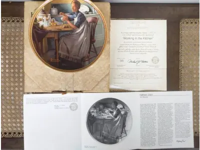 LOTE 342 - 01 PRATO DE COLECIONADOR VINTAGE NORMAN ROCKWELL "WORKING IN THE KITCHEN" "EM PORTUGUES TRABALHANDO NA COZINHA", EDIÇÃO 9 DA COLEÇÃO 'MULHERES REDESCOBERTAS DE ROCKWELL'.A ARTISTA MAIS AMADA DOS ESTADOS UNIDOS APRESENTA UMA SÉRIE INTITULADA "MULHERES REDESCOBERTAS DE ROCKWELL". ESTA É A NONA EDIÇÃO DA SÉRIE “TRABALHANDO NA COZINHA”.PRATO DE NUMERO 1003 K DA EDIÇÃO LIMITADA. EDWIN M, KNOWLES FINE CHINA, NÚMERO BRADEX 84-R70-4.9. COM CERTIFICADO DE AUTENTICIDADE E HISTÓRICO ESCRITO DA IMAGEM DA PLACA INCLUÍDOS. COM DIÂMETRO DE 21 CM CAIXA ORIGINAL. PRATO COM NOTA FISCAL DA ÉPOCA COMPRADO EM 13/09/1983.EM EXCELENTE ESTADO. O SUPORTE DO PRATO NÃO ESTÁ INCLUÍDO. PEÇA COMPRADA EM GARAGEM DE ANTIGUIDADES NOS EUA. SUPORTE PARA PRATO NÃO INCLUÍDO NESTA VENDA. (NO ESTADO) ATENÇÃO! FAZER A VISITAÇÃO ANTES DE ARREMATAR, NÃO SABEMOS SE FUNCIONA, LEILÃO NÃO TEM GARANTIA E NEM DEVOLUÇÃO, SUJEITO A POSSÍVEIS AVARIAS VISÍVEIS/OCULTAS E/OU AUSÊNCIA DE COMPONENTES.