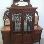 LOTE 040 - 01 CRISTALEIRA ANTIGA IMBUIA COM DETALHES ENTALHADOS NAS PORTAS, ESPELHOS LATERAIS, COM PORTA ENVIDRAÇADA EM CRISTAL BISOTADO. (NO ESTADO DE CONSERVAÇÃO QUE SE ENCONTRA) 